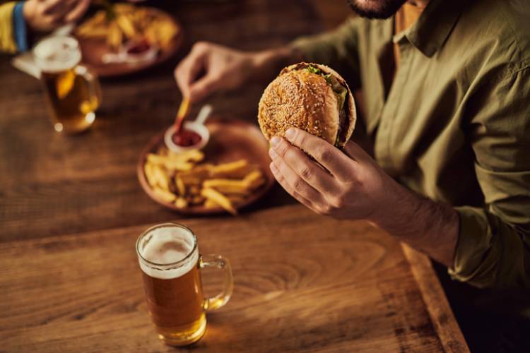 A man eating a burger with a beer
