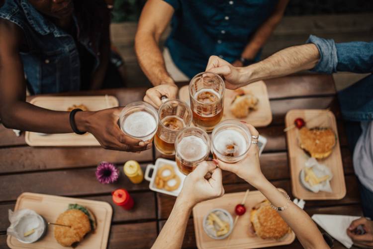 People cheering beers over burgers